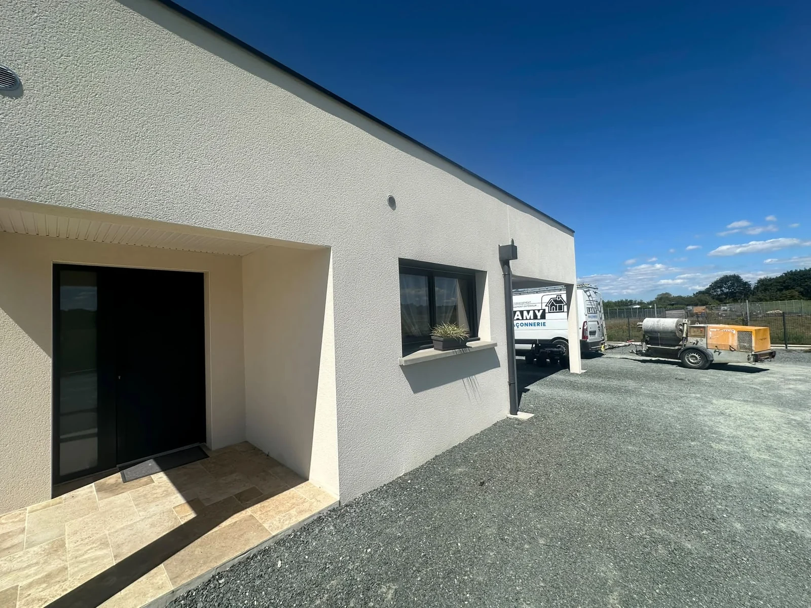 Façade de maison avec enduit et véhicule LAMY Maçonnerie
